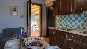 A dining area with a table set for two, a sofa, and a view of the outdoors. - Pet-friendly Cottage With Pool (Bettona)