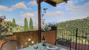 A table set outdoors with a view of a hilly landscape, a bottle of wine, and a newspaper. - Pet-friendly Cottage With Pool (Bettona)