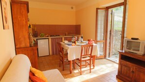 Un espacio habitable compacto con comedor, kitchenette y televisor.