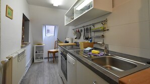 Una cucina compatta con forno a incasso, lavello e finestra che permette luce naturale.