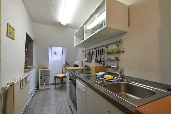 A compact kitchen with a built-in oven, a sink, and a window providing natural light. - Stilvolle Wohnung mit Garten in Kluetz (Klütz)
