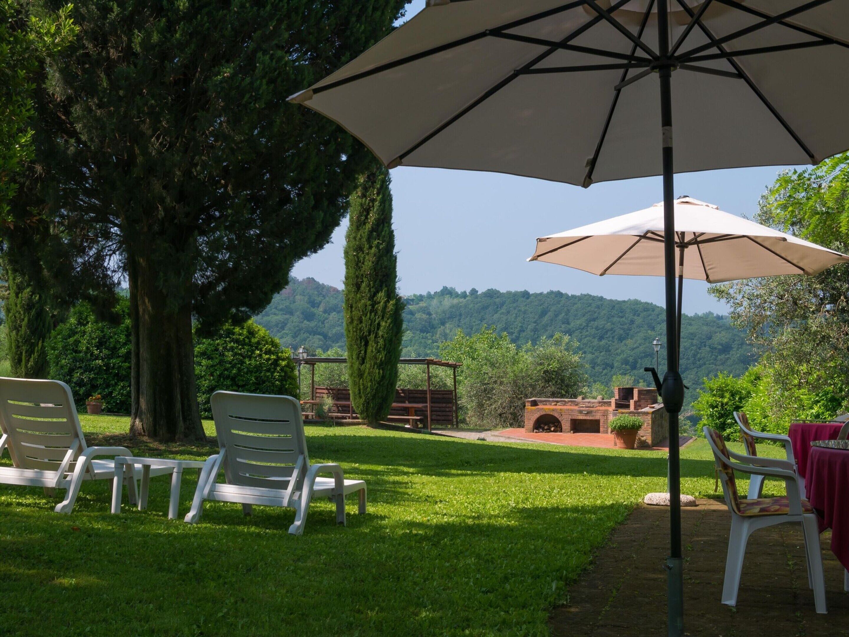 A patio area with outdoor seating and a view of a forested hill.