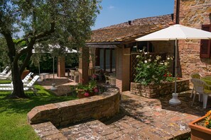 A patio area with a stone wall, outdoor seating, and a pool. - Charming Retreat in Montaione (Montaione)