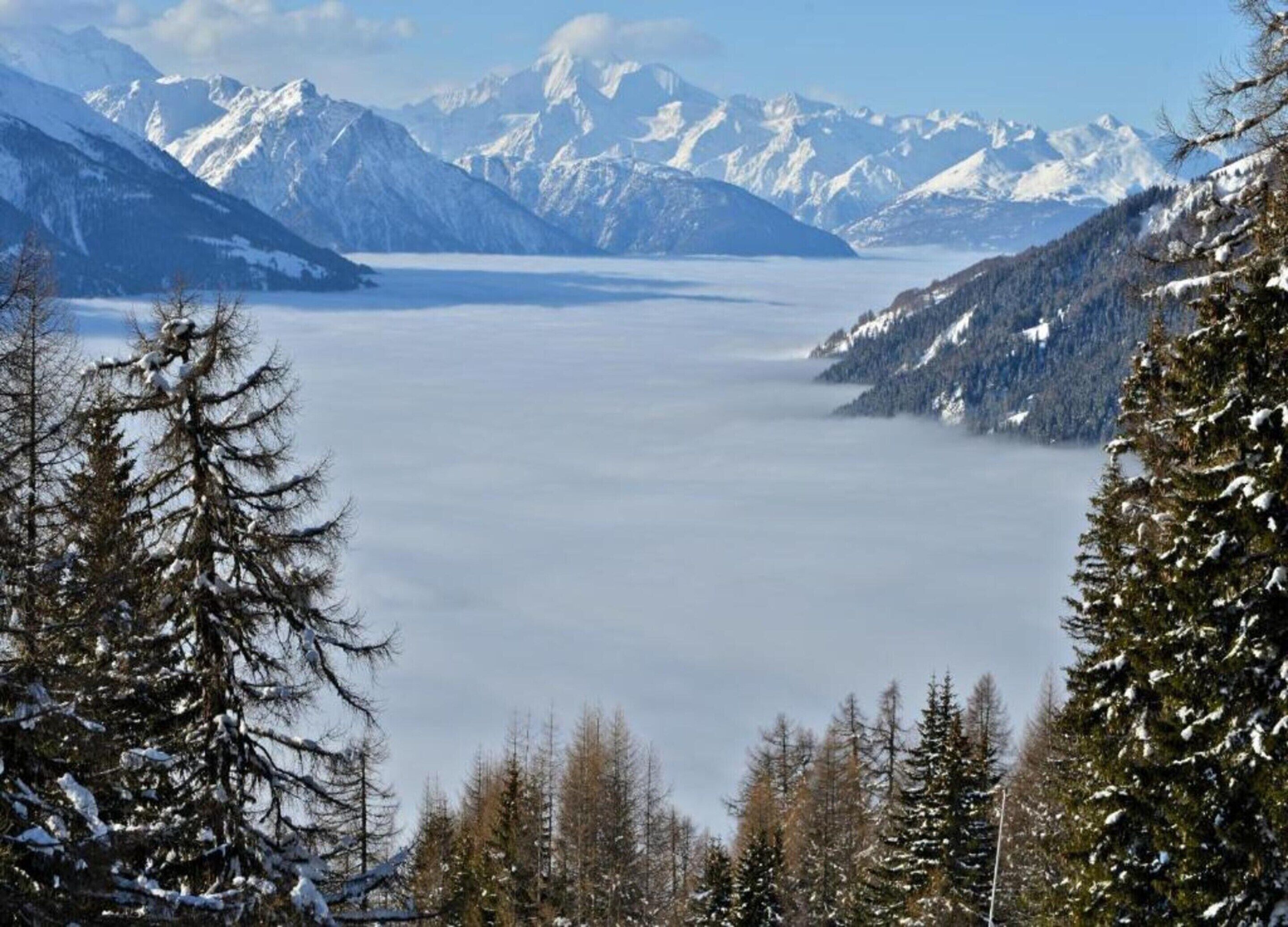 Un paysage montagneux avec des sommets enneigés et un lac.