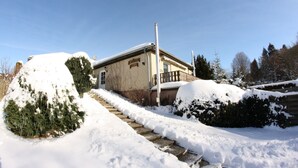 Ein schneebedecktes Gebäude mit Ziegelaußenwand, einem sichtbaren Eingang und einer kleinen Veranda.