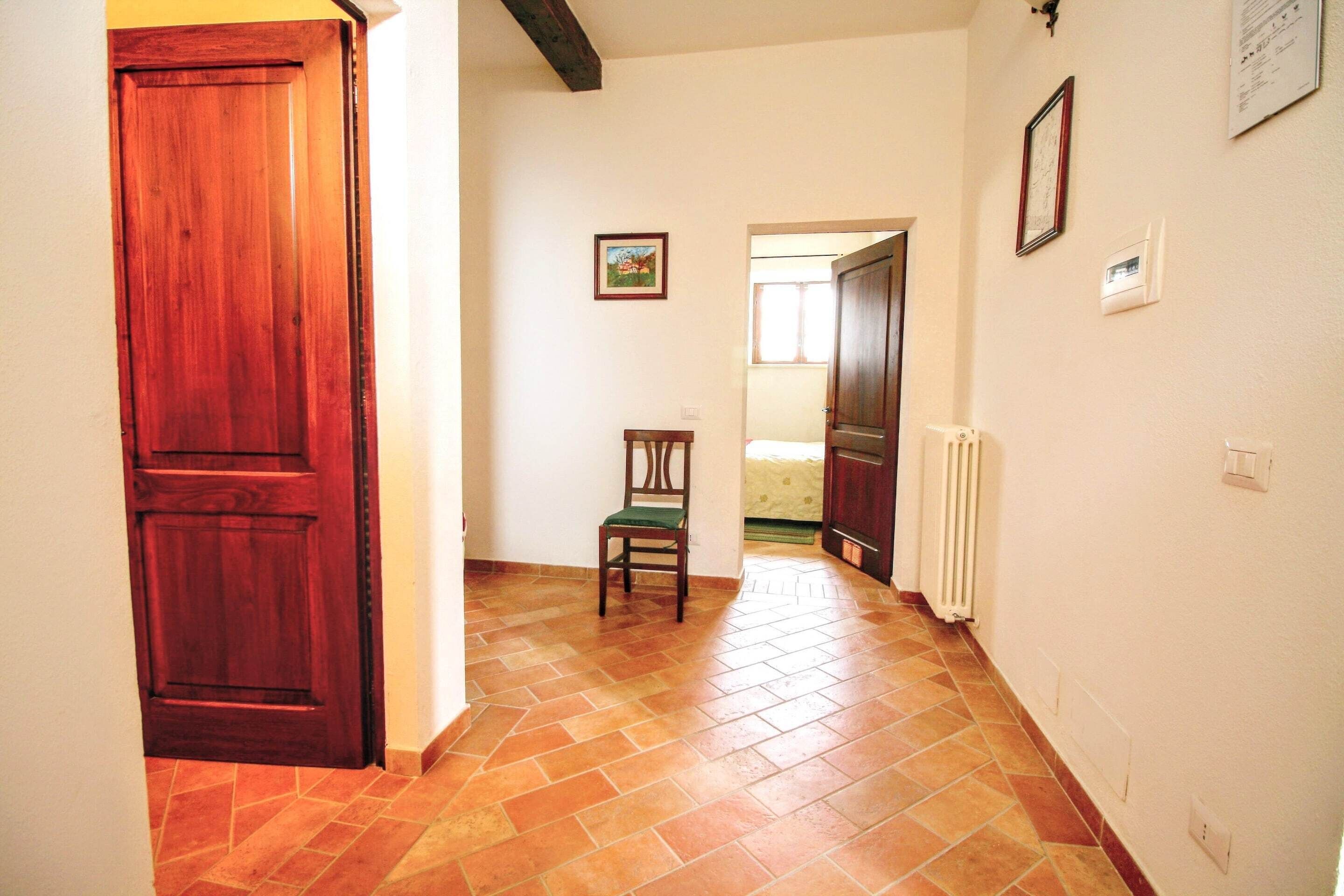 A hallway with a wooden door, a chair, a radiator, and a framed picture on the wall.