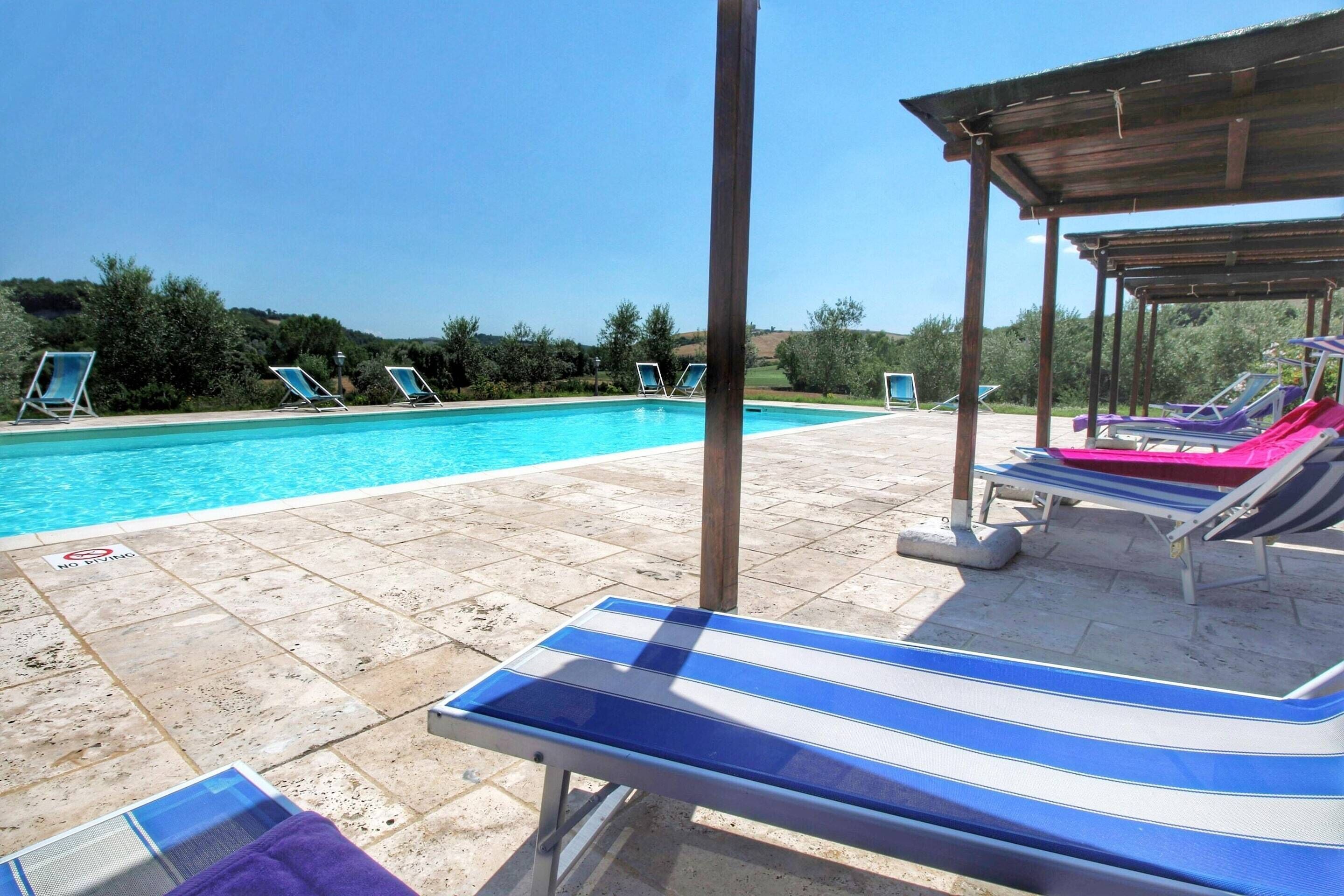 Piscina con sillas de descanso y una zona cubierta.