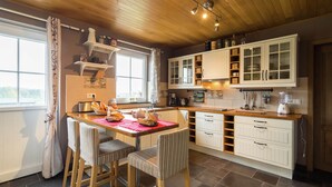 Una cocina con armarios de madera, una mesa de comedor con sillas y una ventana con cortinas.