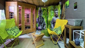 Una habitación con techo de madera, una gran estatua de Buda, dos sillas verdes, una pequeña mesa de madera y una cesta de mimbre en un estante.