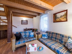 Ein gemütliches Wohnzimmer mit zwei karierten Sofas, einer Holzbalkendecke und einem Gemälde an der Wand.