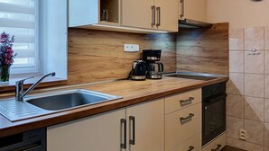 A modern kitchen with wooden countertops, a built-in coffee maker, and a clock on the wall.