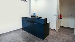 A reception desk with a computer monitor, an air conditioning unit, and a fire extinguisher. - Capital O 67657 Schmear Suites (Bengaluru)