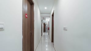 A clean, well-lit hallway with doors marked by numbers, leading to different rooms. - Capital O 67657 Schmear Suites (Bengaluru)