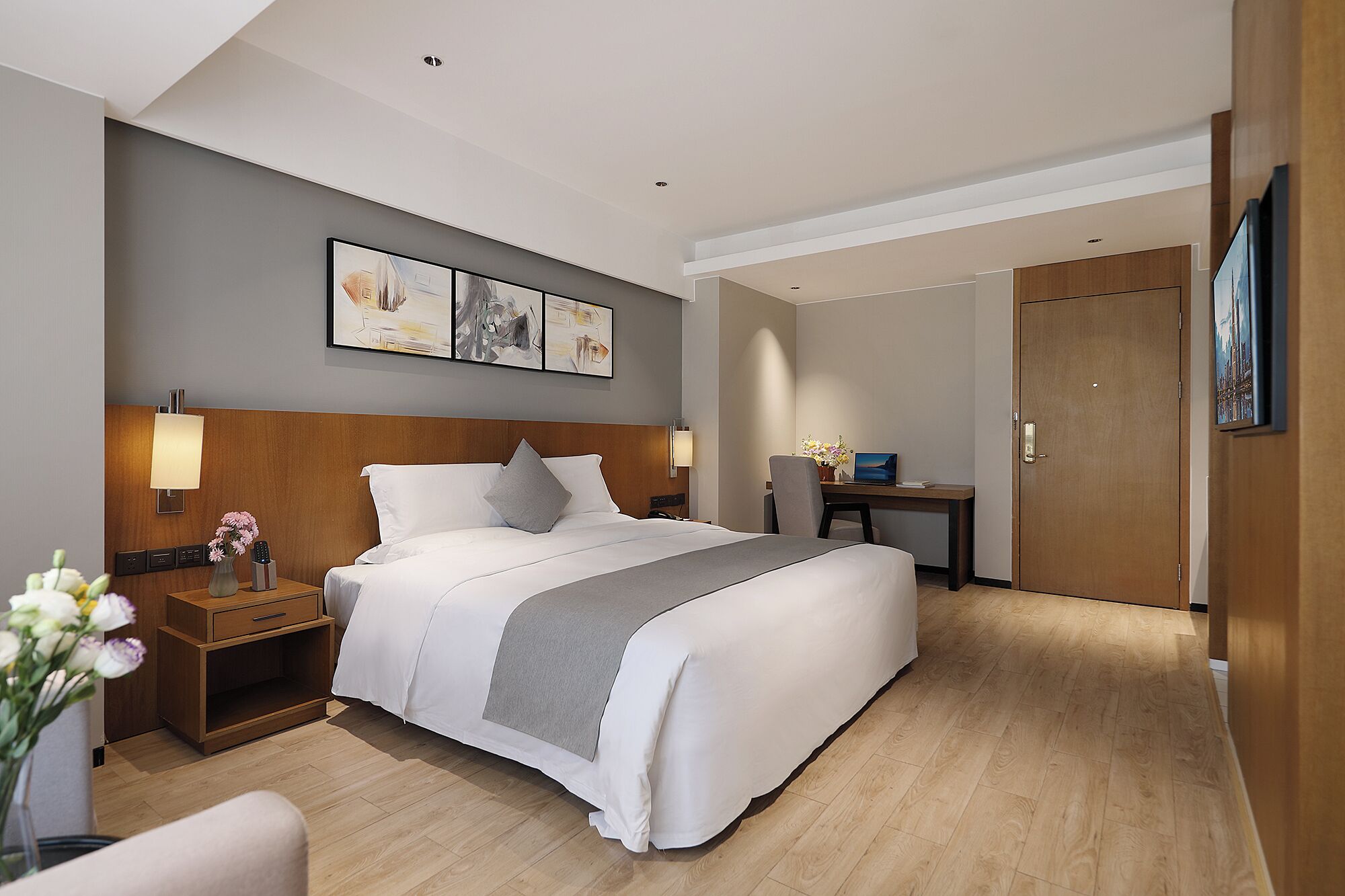 Una habitación de hotel con una cama grande, mesitas de noche, un escritorio y una puerta.