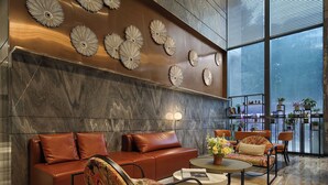 A modern lobby with leather sofas, a round coffee table, and decorative wall art. - Shenzhen Hongdu Hotel (Shenzhen)
