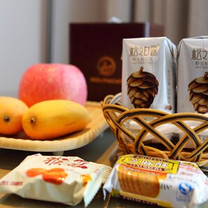 A table with a basket containing bread, a plate with apples, and a package of bread.