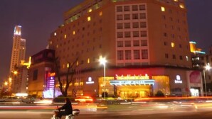 A multi-story hotel with a prominent sign at the entrance, multiple windows, and a flat roof.