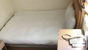 A single bed with a white sheet, a wooden bedside table with a telephone, and a box on the floor. - Huasin Hotel (Jincheng)