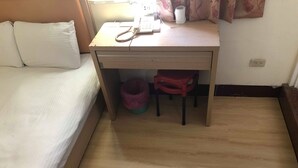 A small room with a bed, a desk, and a trash bin. - Huasin Hotel (Jincheng)