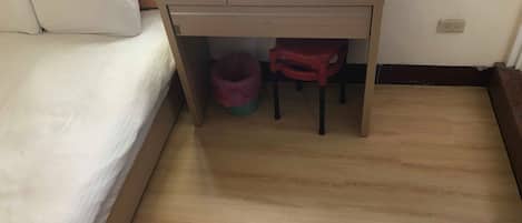 Una habitación pequeña con una cama, un escritorio y un bote de basura.