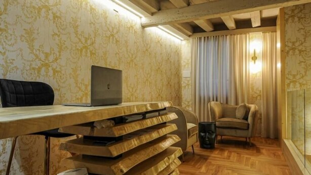 Um quarto com escrivaninha de madeira, um laptop, uma cadeira e um sofá.