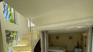 A spacious room with a bed, a desk, and a staircase leading to an upper level. - DUPLEX APARTMENT, SEA VIEW (La Cadière-d'Azur)