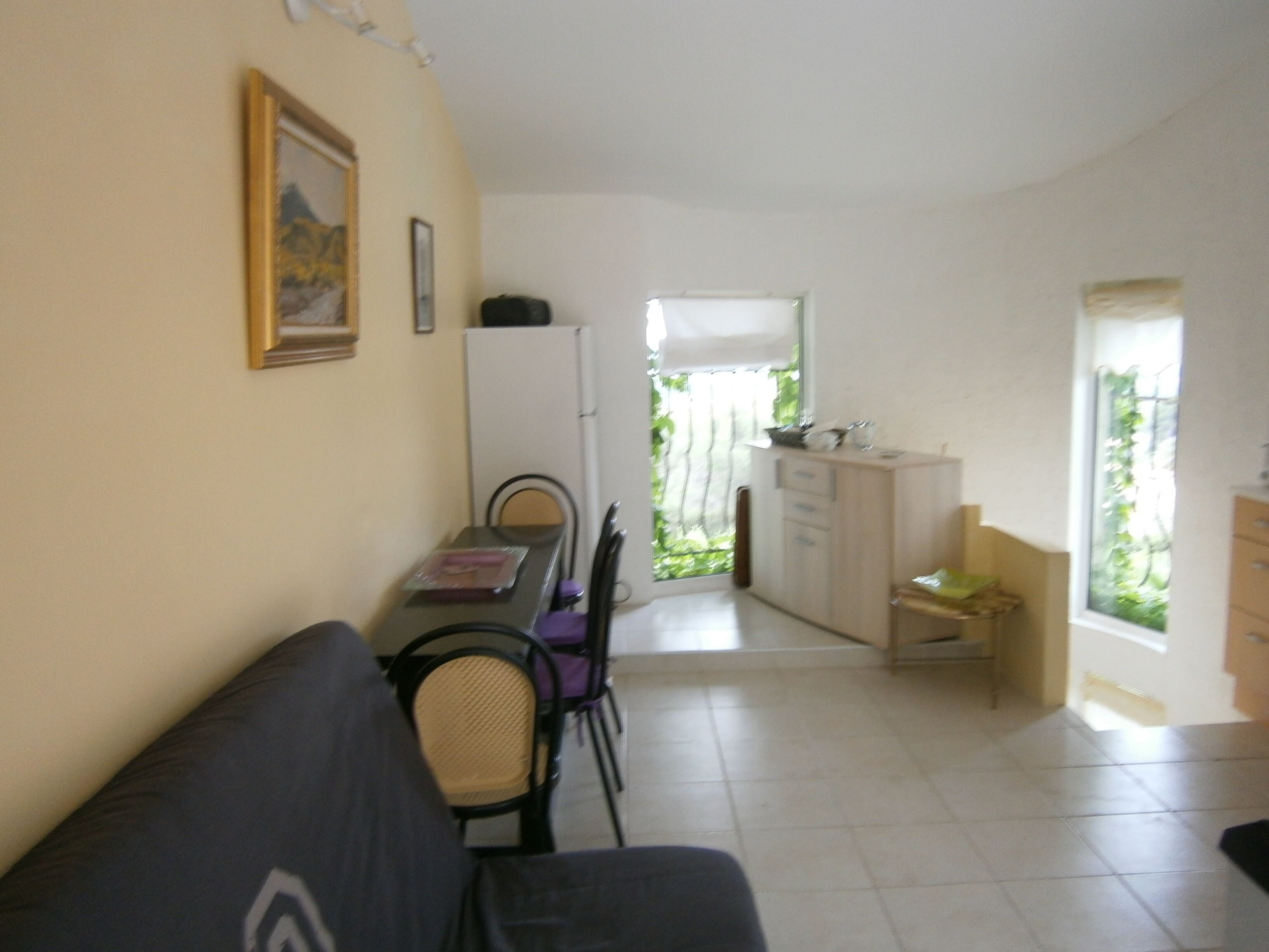 A compact living space with a dining area, kitchenette, and a window providing natural light.
