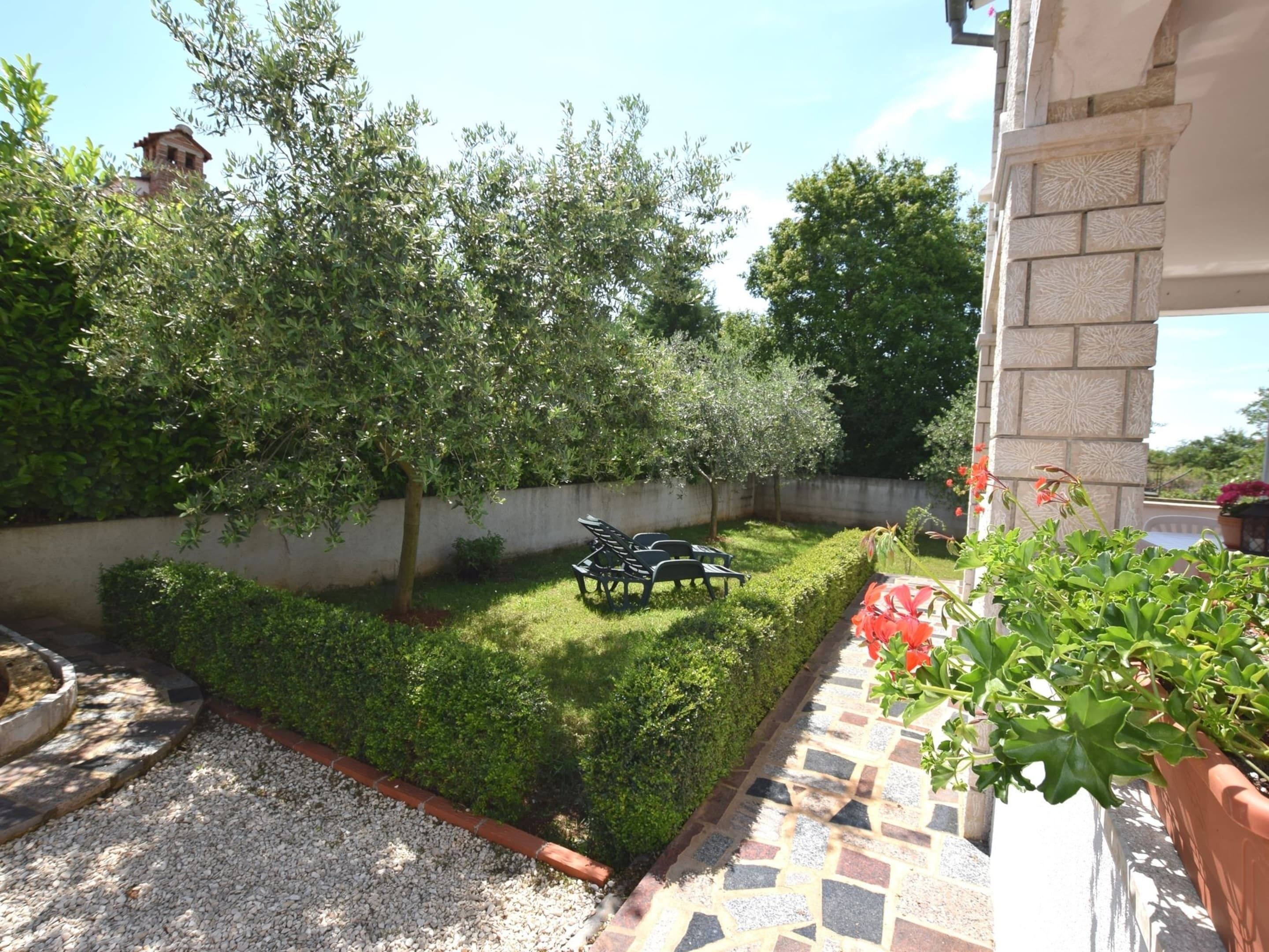 A garden with a paved patio, a bench, and a wall with a decorative pattern.