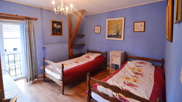 Ein Schlafzimmer mit zwei hölzernen Betten, einer Chandelüster und einem Fenster mit Vorhängen.