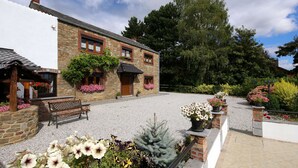 A stone building with a gravel courtyard, benches, and potted plants. - Family House with Large Garden & Games Room near Bambois Lake (Mettet)