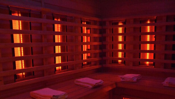 Un sauna avec des bancs en bois, chacun étant muni d’une serviette.