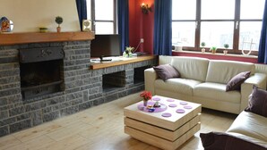 Un salon avec une cheminée en pierre, un canapé, une table basse et une fenêtre avec des rideaux.