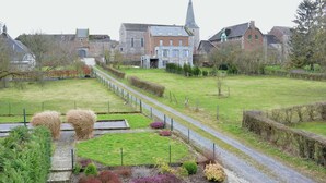 Un village rural qui se distingue par sa grande église, un chemin pavé et une grande variété de plantes à fleurs.