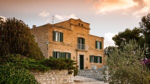 A stone building with a balcony, surrounded by greenery and a gravel path. - Villa in Paceco Near Marsala Beaches (Paceco)