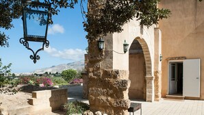 An outdoor dining area with a table set for four, surrounded by stone walls and a view of the countryside. - Villa in Paceco Near Marsala Beaches (Paceco)