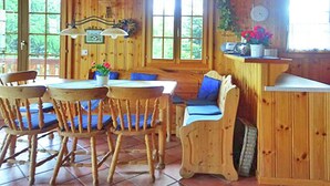 Interior de una cabaña de madera con comedor, zona de estar y mostrador de cocina.