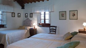 A bedroom with two beds, a chair, a window with curtains, and framed pictures on the wall. - Apartment in Tuscany With Stunning Hilltop Views (Pergine Valdarno)