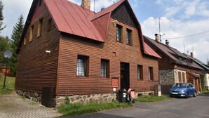 A two-story wooden house with a sloped roof, a stone foundation, and a small attached garage. - Lavish Holiday Home in Abertamy near Ski Area (Abertamy)