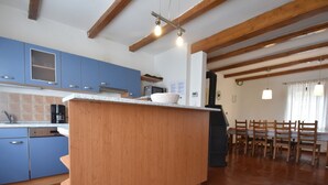 A kitchen with blue cabinets, a wooden island, and a dining area with wooden chairs and a table. - Lavish Holiday Home in Abertamy near Ski Area (Abertamy)