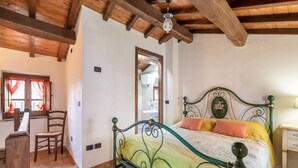 Un dormitorio con estructura de cama metálica verde, colcha amarilla y techo de madera.