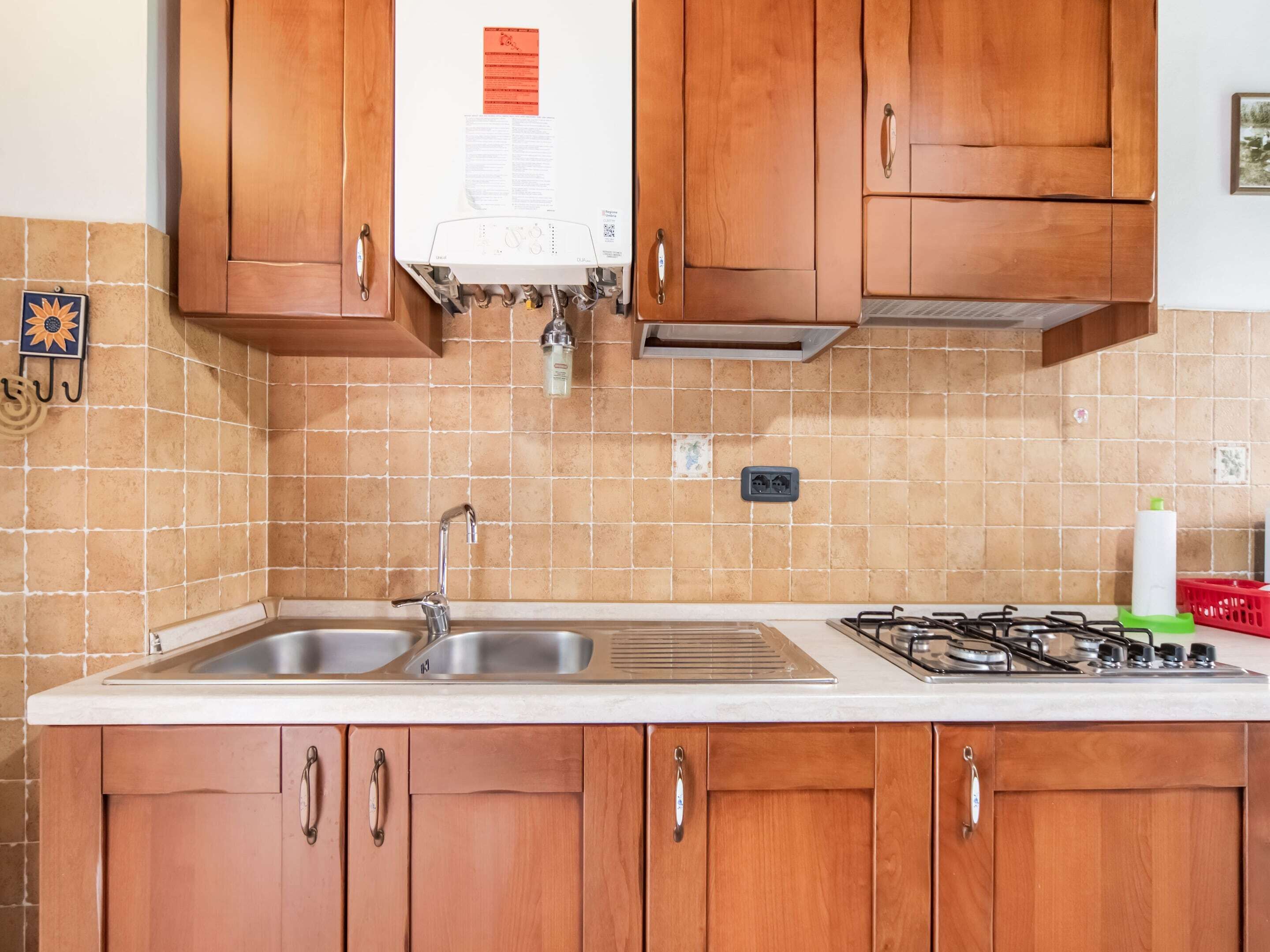 Una cocina con armarios de madera, un lavamanos doble, una estufa a gas y un salpicadero de azulejos.