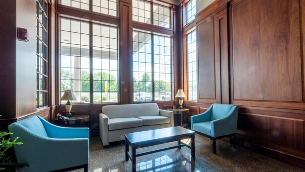 A spacious lobby with large windows, a sofa, two armchairs, and a coffee table. - HomeTowne Studios by Red Roof Wilmington - New Castle (New Castle)