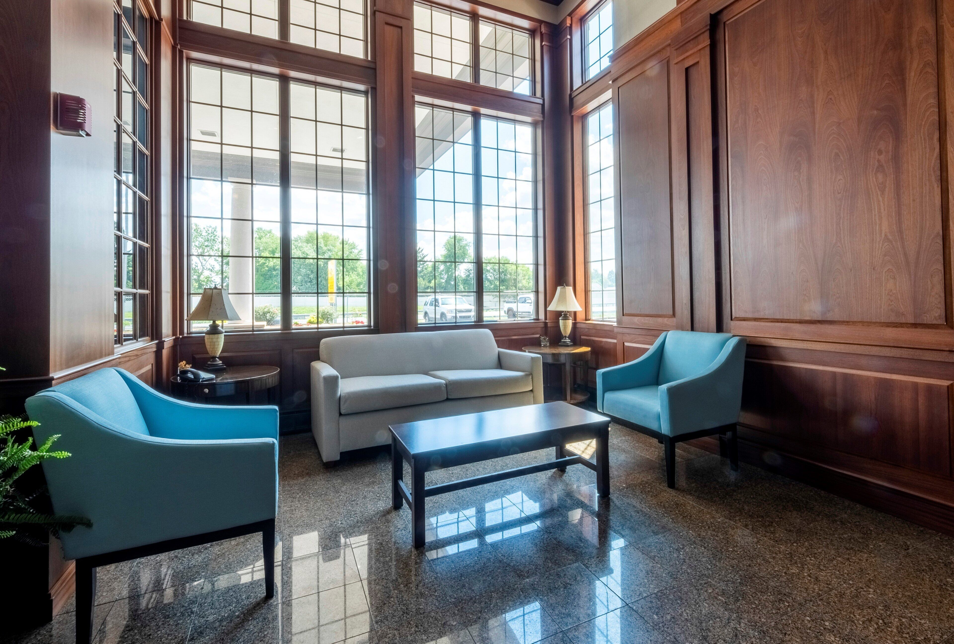 A spacious lobby with a large window, a sofa, two armchairs, and a coffee table.