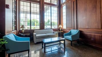 A spacious lobby with a large window, a sofa, two armchairs, and a coffee table.