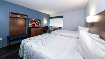 A hotel room with two beds, a desk with a chair, a TV, and a window with blinds.
