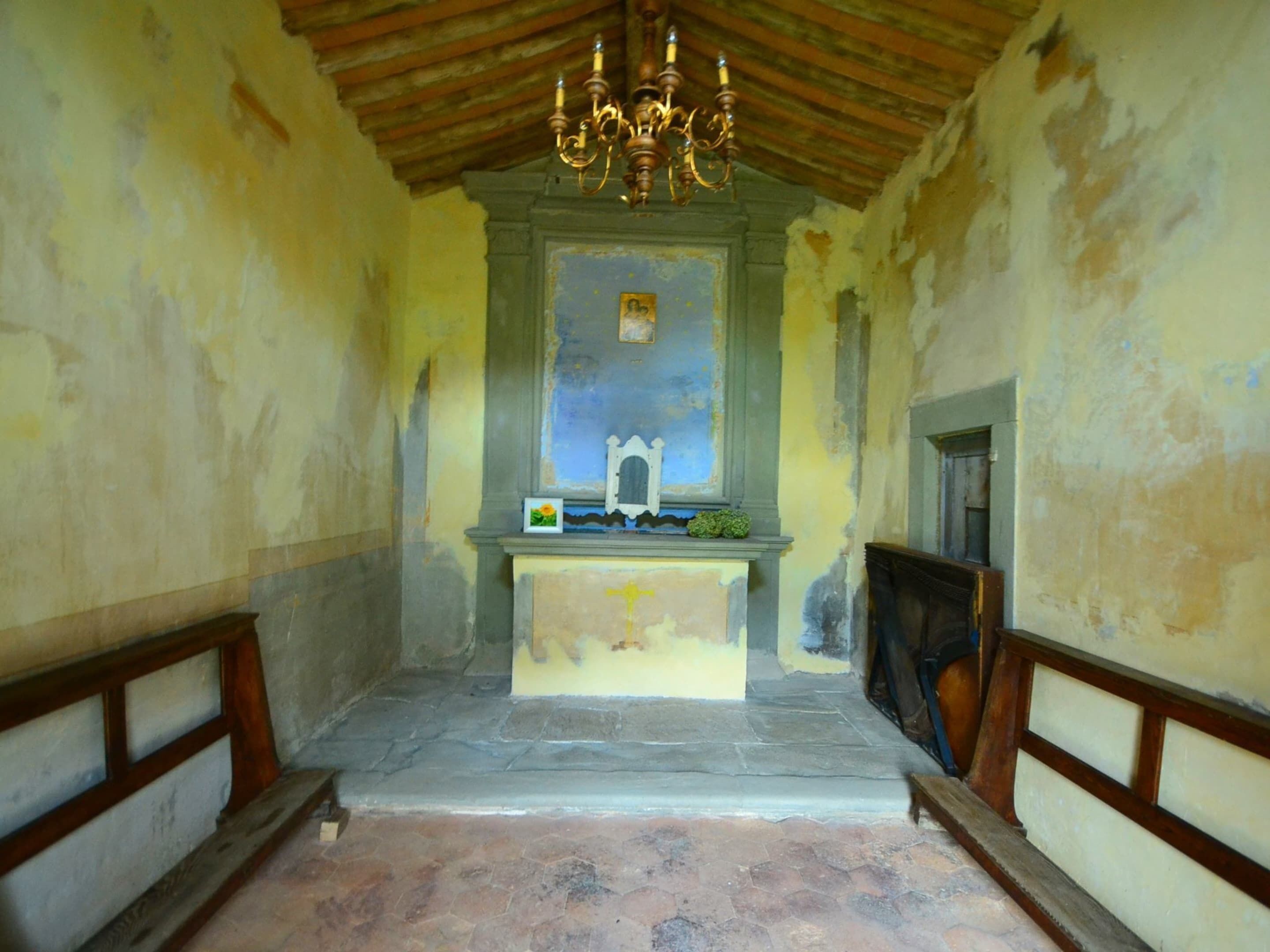 A chapel with a stone altar, a wooden bench, and a chandelier.