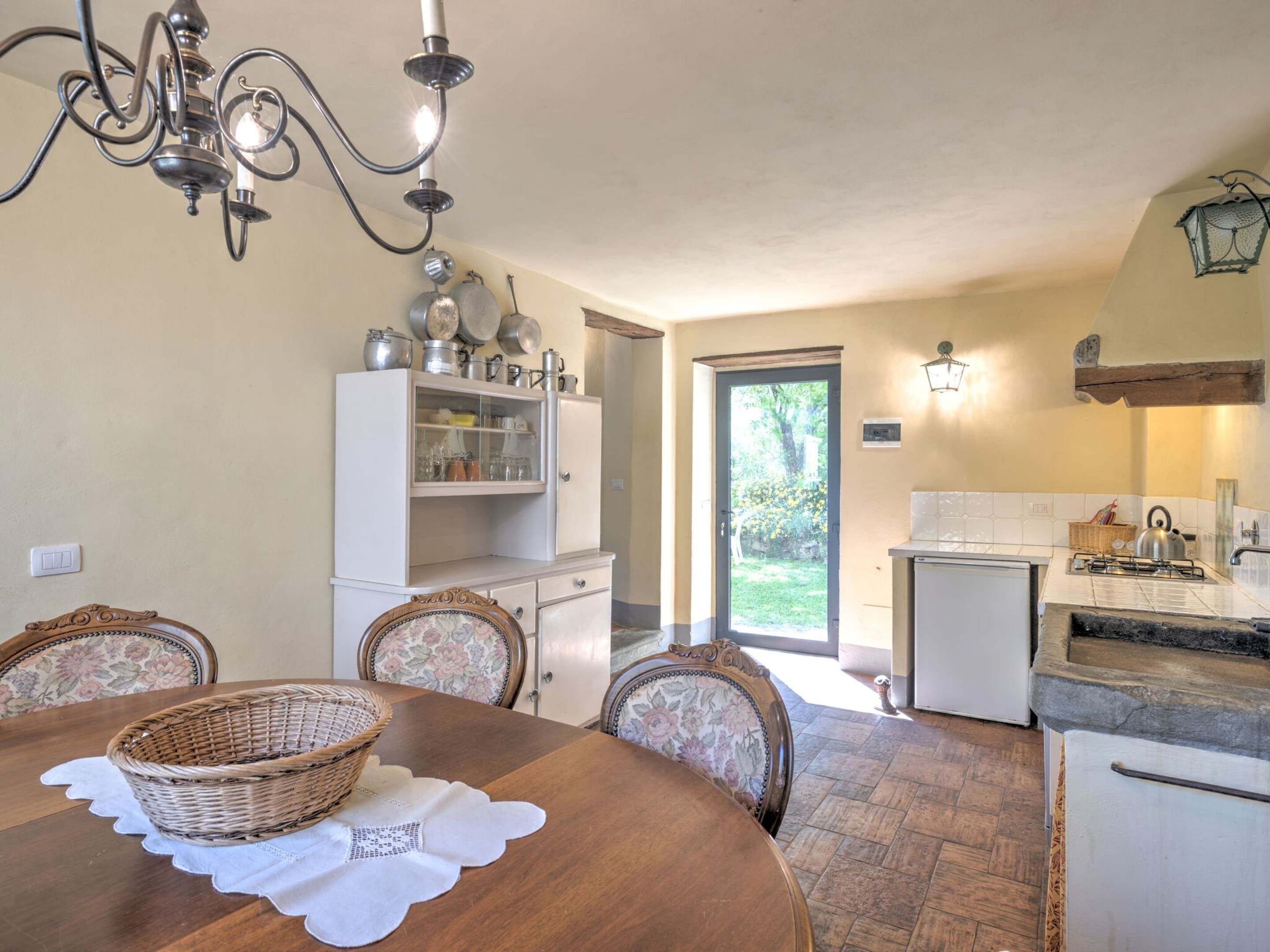 A dining area with a wooden table, wicker baskets, and a white cabinet with dishes.