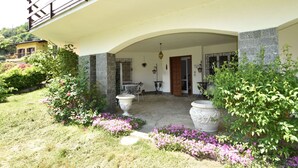 A building with a balcony, a stone entrance, and a garden with flowers. - Belvilla by OYO Villino Lucrezia (Meina)