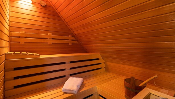 A sauna with wooden benches and a bench with a towel. - Ferienhaus Silbermöwe - Haus Silbermöwe (Loddin)