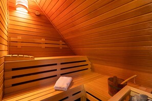 A sauna with wooden benches and a bench with a towel.